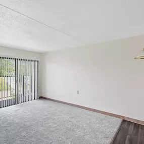 A room with a grey carpet and a white wall with a hanging light fixture