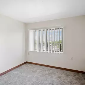 A room with a window covered by white blinds