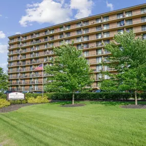A large apartment building with a lawn in front and a sign that says
