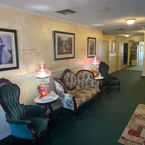 Discover the inviting foyer at Watts Funeral Homes, featuring vintage seating, ornate lamps, and warm décor that create a comforting environment for families.