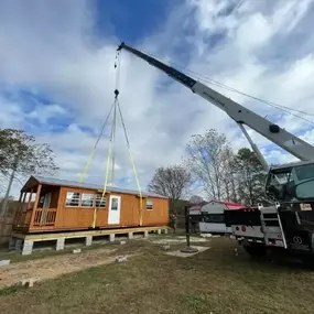 Heavy-duty crane placing a modular cabin on foundation in North Carolina.