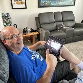 A satisfied customer in Escondido, CA, relaxing on their couch while reviewing their newly installed AI-powered security camera system on a tablet. Installed by NextGen Technology Solutions, this advanced system offers remote monitoring, motion detection, and 24/7 surveillance, providing complete security and peace of mind.