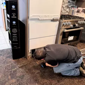 A Voss technician performs maintenance on a high-end built-in refrigerator unit in the showroom.