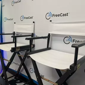 A professional interview and media production setup at FreeCast, Inc., showcasing two stylish white director’s chairs positioned in front of a branded FreeCast backdrop.