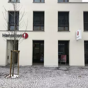 Hansaton Hörkompetenz-Zentrum Raiffeisenstraße 1a, Lustenau von der gegenüberliegenden Straßenseite kommend