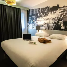 Chambre double de l’hôtel Ibis Styles Paris Tolbiac Bibliothèque avec une tête de lit inspirée d’un pont de Paris.