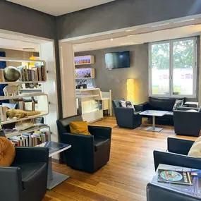 Espace détente de l’hôtel Ibis Styles Paris Tolbiac Bibliothèque, avec canapés, fauteuils et bibliothèque décorative.