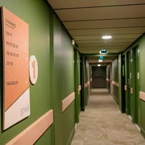 Les couloirs du Greet Hôtel Montpellier sont aménagés dans des tons kaki apaisants, agrémentés de matériaux naturels comme le bois et le liège. Une décoration moderne et éco-responsable qui invite à la détente et à la tranquillité, reflétant l'engagement durable de l’établissement.