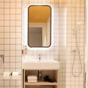 Private bathroom in the studio apartments of Adagio Acces Brussels Airport Hotel. It contains a toilet, shower with soap amenities, hair dryer and towels.