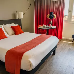 Chambre lumineuse de l’hôtel ibis Alès Centre-Ville avec vue sur le centre-ville.