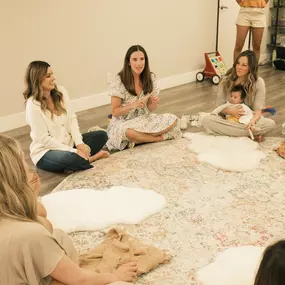 New moms sit in a circle listening and laughing with the teachers