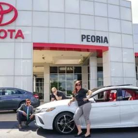 Peoria Toyota team members posing outside dealership with a car