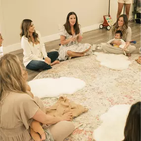 New moms sitting in a circle on the floor across from two instructors