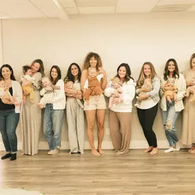 Eleven new moms holding their babies line up posing for a photo