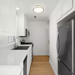 A kitchen with white cabinets and a black fridge