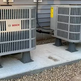 High-efficiency Bosch HVAC outdoor units installed on a concrete platform outside a residential home. These energy-efficient heating and cooling systems provide reliable climate control for year-round comfort. MAX Comfort HVAC specializes in professional HVAC installation and maintenance in Allentown, PA, ensuring optimal performance and efficiency.