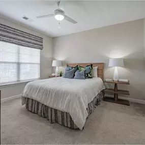 A bedroom with a bed, two lamps, and a window with blinds