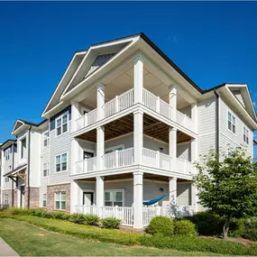 A white two-story apartment building with a balcony on the second floor