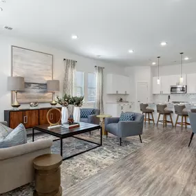 A beautifully designed open-concept living room and kitchen featuring modern furnishings, warm lighting, and a neutral color palette.