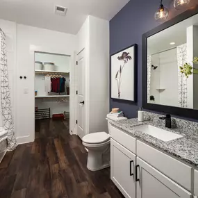 Bathroom with soaking bathtub, linen closet, and walk-in closet with wood-style flooring at Camden West Nashville apartments in Nashville, TN