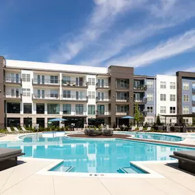 Resort-style pool with seating and deck in the middle with a firepit at Camden West Nashville apartments in Nashville, TN