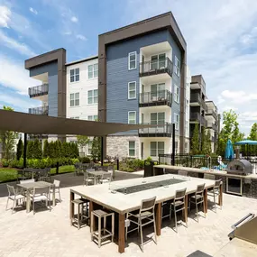 Outdoor kitchen with gas grills, pizza oven, gas fire table, and covered seating at Camden West Nashville apartments in Nashville, TN