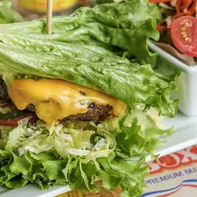 Delicious cheeseburger served protein style with lettuce and a side salad.