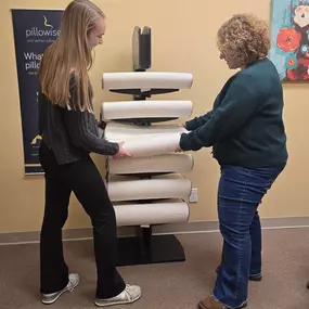 Allison, chiropractic assistant at Healthy Lifestyles Chiropractic handing a therapeutic pillow to a patient