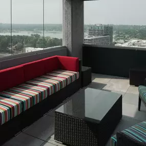 A red couch with a striped pattern sits in a room with a view of the city.