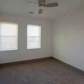 A room with a ceiling fan and carpeted floor.