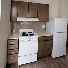 A white stove and refrigerator in a kitchen with brown cabinets.