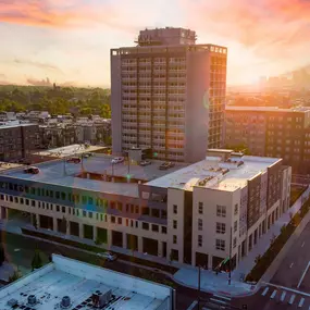 A cityscape with a large building in the foreground and a sunset in the background.