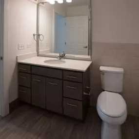 A bathroom with a toilet, sink, and mirror.