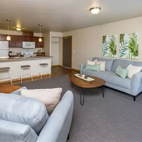 a living room with a couch and a table in front of a kitchen
