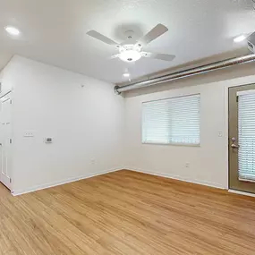 A room with a ceiling fan and wooden flooring