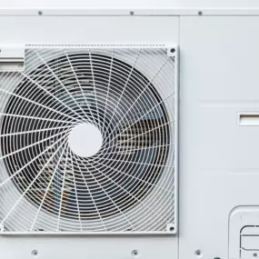 Das Bild zeigt eine moderne Außen-Einheit einer Wärmepumpe, die zur energieeffizienten Beheizung von Gebäuden eingesetzt wird. Der große Ventilator sorgt für den Wärmeaustausch mit der Umgebungsluft und ermöglicht eine nachhaltige Heizlösung für private und gewerbliche Immobilien.