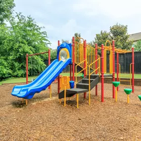 A playground with a blue slide and yellow and red play structures.