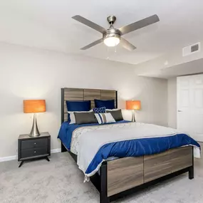 A bedroom with a bed, nightstands, and a ceiling fan.