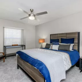 A bedroom with a bed, chair, and lamp.