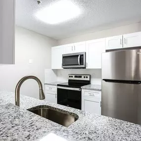 A kitchen with a granite countertop and stainless steel appliances