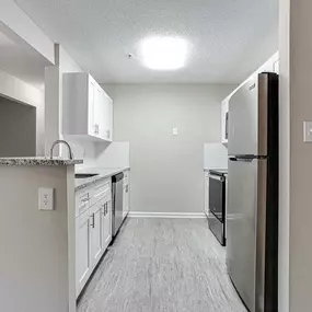 A kitchen with a refrigerator, cabinets, and a counter.