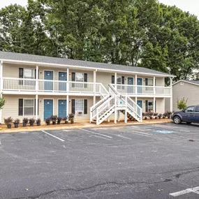 A two-story building with a blue car parked in front.