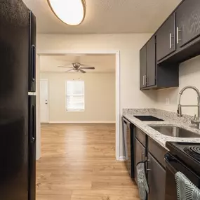 A kitchen with a black refrigerator and black stove.