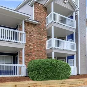 a building with two balconies and a bush in front of it