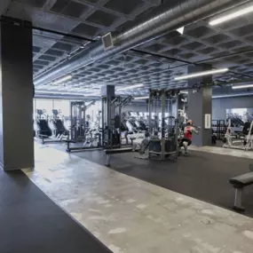 A gym with various exercise equipment and a person working out.