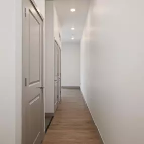A long hallway with white walls and wood floors.