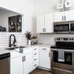 A modern kitchen with white cabinets and a black stove top.