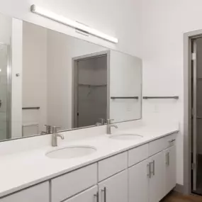 A bathroom with a white counter top and a sink.