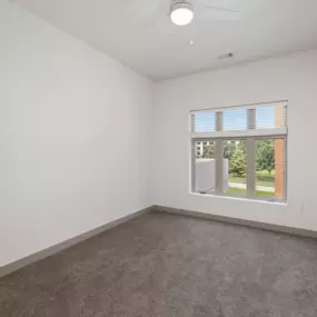 A room with a window and a fan on the ceiling.