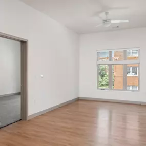 A room with a ceiling fan and a window with blinds.